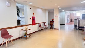 En reception med disk, stole, en plante og en brandalarm.