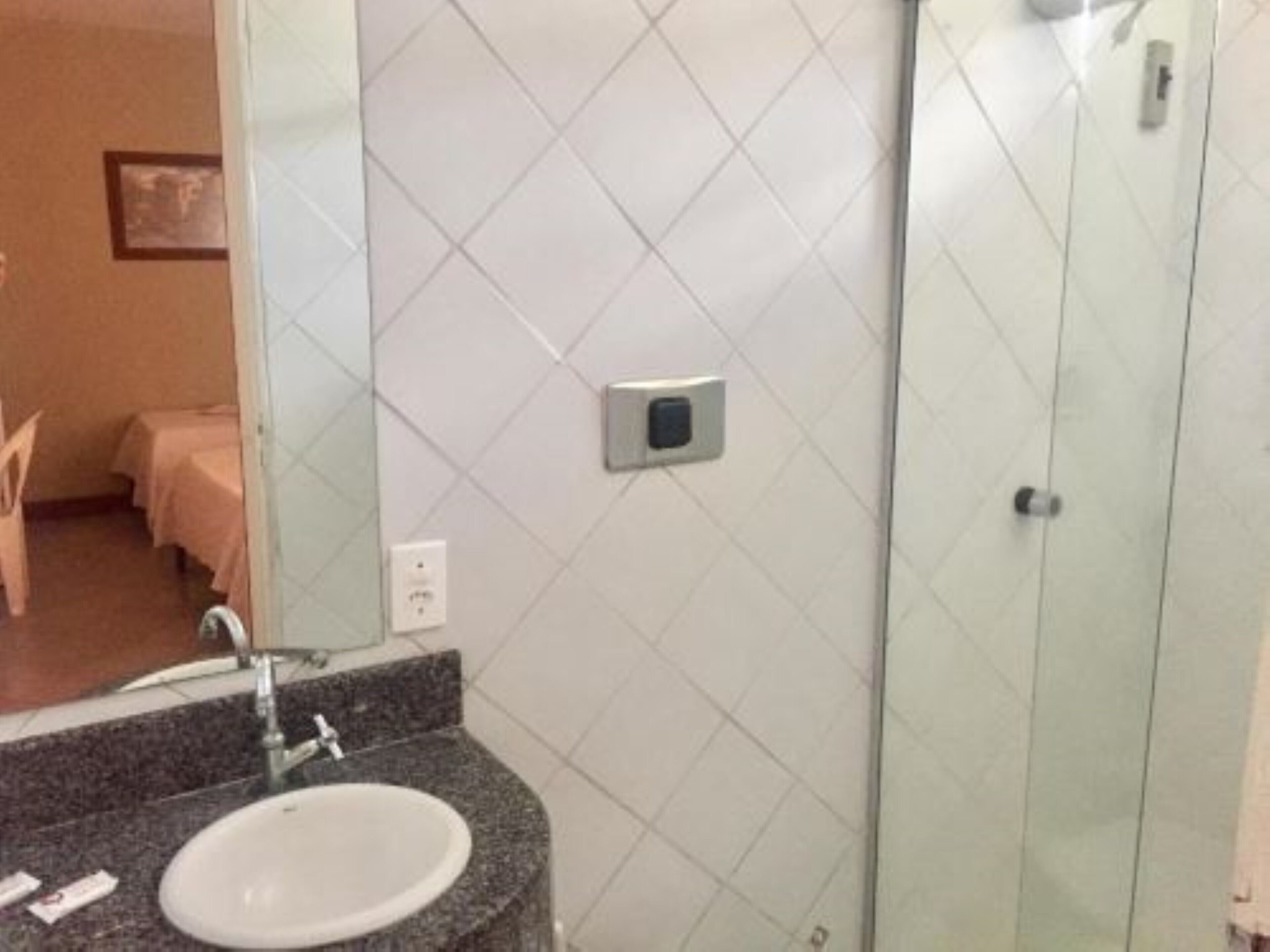 A bathroom with a granite countertop sink, a mirror, and a glass shower enclosure.
