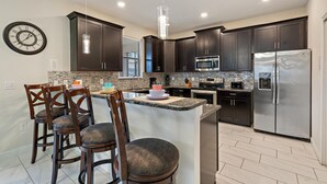Una cocina moderna con armarios de madera oscura, electrodomésticos de acero inoxidable y encimera de granito.