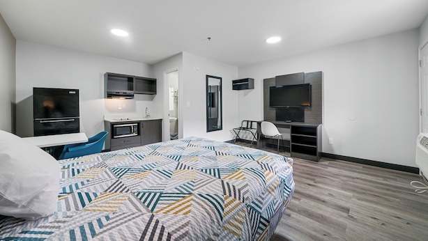 Een moderne hotelkamer met een groot bed, een bureau, een televisie en een kitchenette.