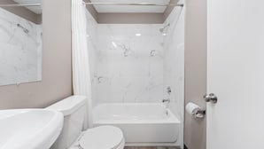 Een moderne badkamer met een bad, toilet en wastafel.