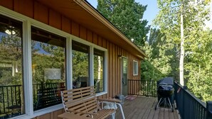 Un patio in legno con due panchine e un barbecue.