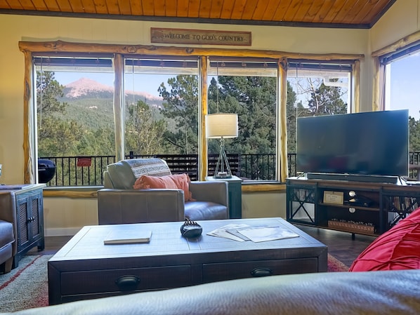 Una sala de estar con un ventanal grande, un televisor, un sofá y una mesa de centro.