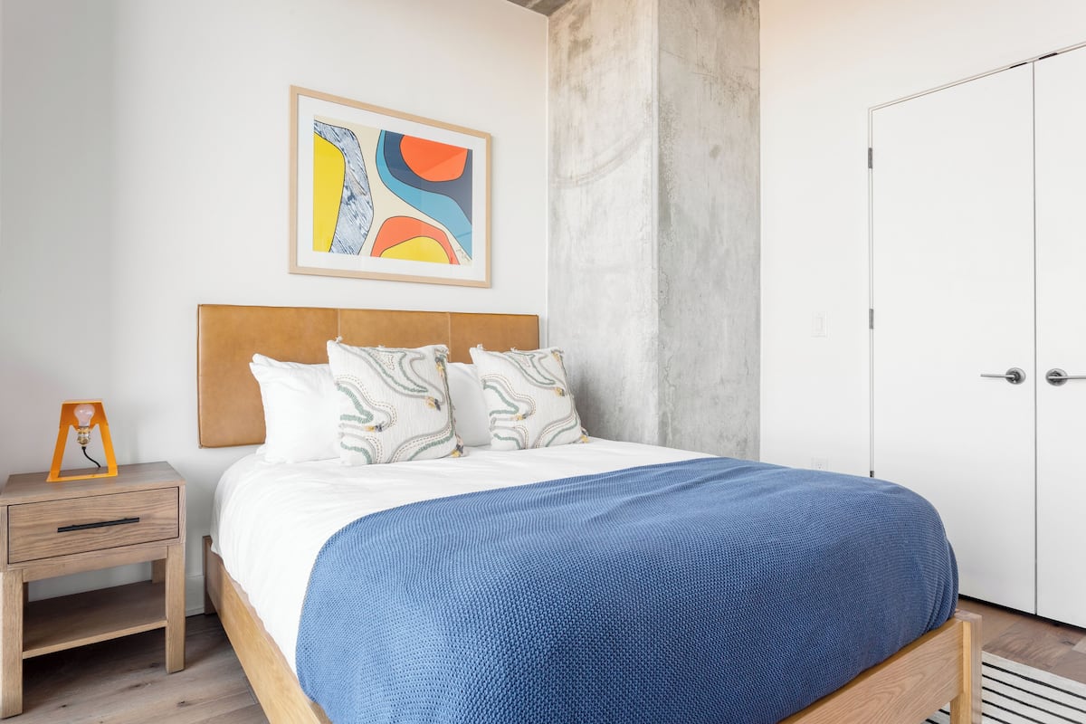 A bedroom with a bed, a nightstand, a wardrobe, and a wall art piece.