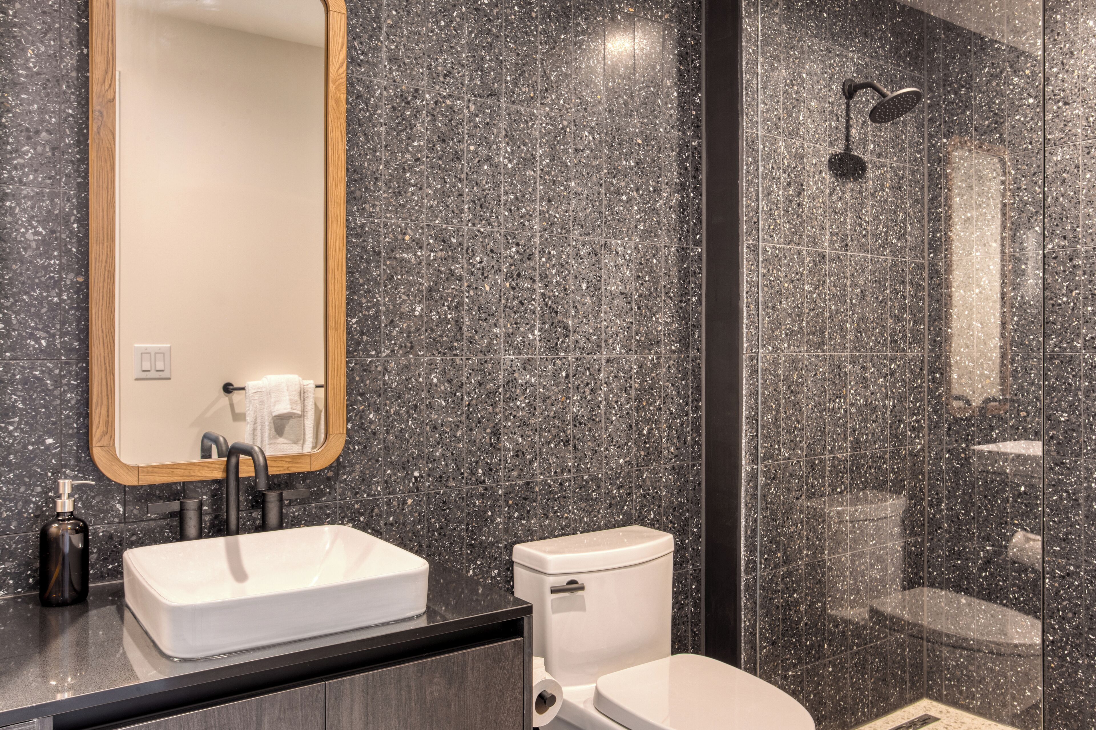 A modern bathroom with a rectangular sink, a toilet, and a shower enclosure.