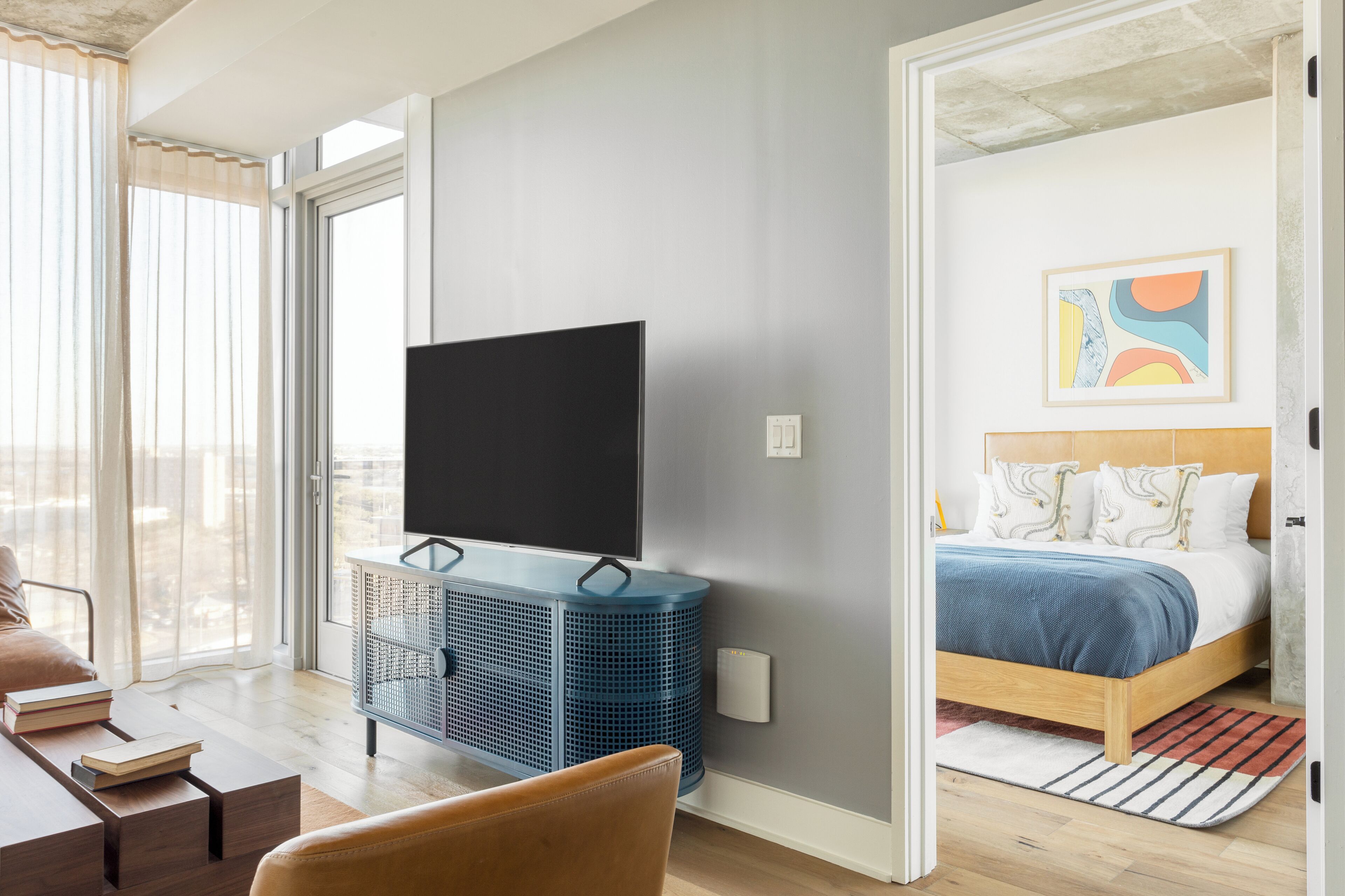 A modern bedroom with a bed, a TV, and a blue storage unit.