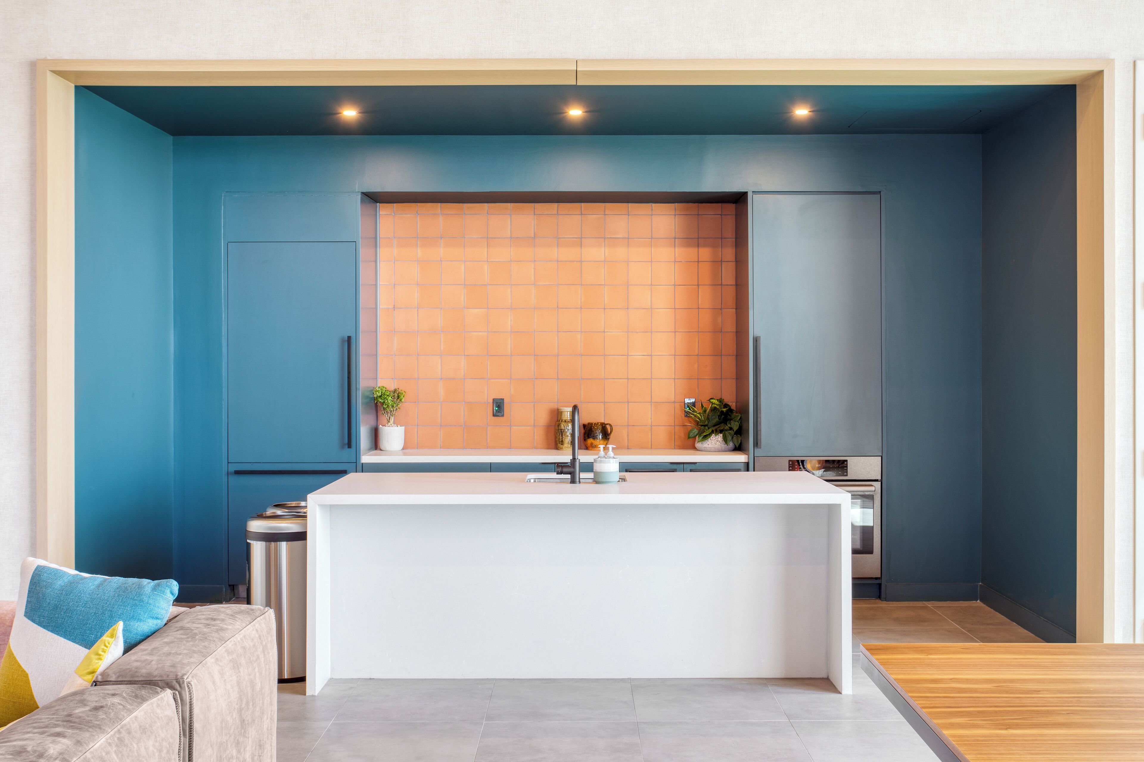 A modern kitchen with a central island, blue walls, and a wooden floor.