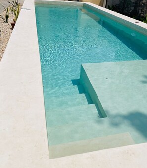 Ein rechteckiger Pool mit klarem, blauem Wasser, umgeben von einer hellen Promenade.