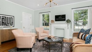 A living room with a fireplace, two armchairs, a sofa, and a coffee table. - Magnolia Cottage | 3/2, Full Kitchen, Hot Tub, Grill, 3 Blocks to Main (Fredericksburg)