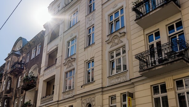 Ein mehrgeschossiges Gebäude mit aufwendigen architektonischen Details, darunter dekorative Gesimse und eine Reihe von Balkonen mit schwarzen Geländern.
