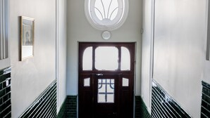 Ein Korridor mit einer großen Holztür, einem Rundfenster und einem gerahmten Bild an der Wand.