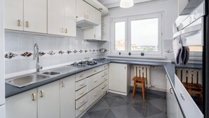 A modern kitchen with white cabinets, a gas stove, a sink, and a window with a view.