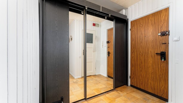 A hallway with a wooden floor, a sliding door, and a wooden door.