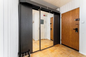 Um corredor com piso de madeira, uma porta deslizante e uma porta de madeira.