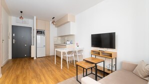 A compact living space with a kitchenette, a dining area, a TV, and a sofa. - Park Skowroni Cosy Apartment (Wrocław)
