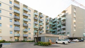 A multi-story residential building with balconies, a parking area, and a small garden. - Park Skowroni Cosy Apartment (Wrocław)
