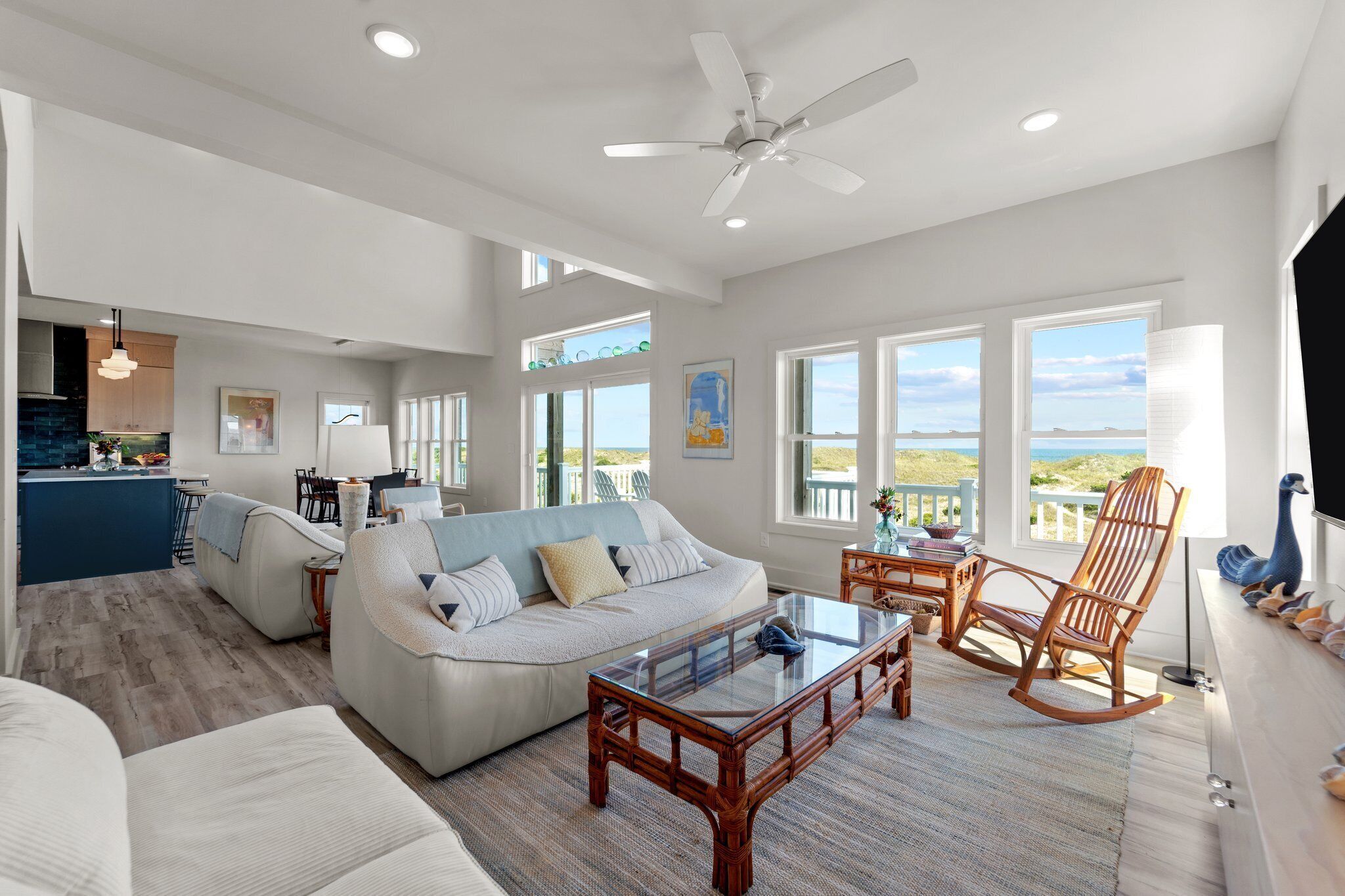 A spacious living area with a large window, a ceiling fan, and a view of the ocean.