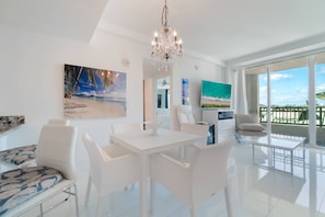 Uma sala de estar moderna com um conjunto de jantar branco, um candelabro e obras de arte nas paredes.