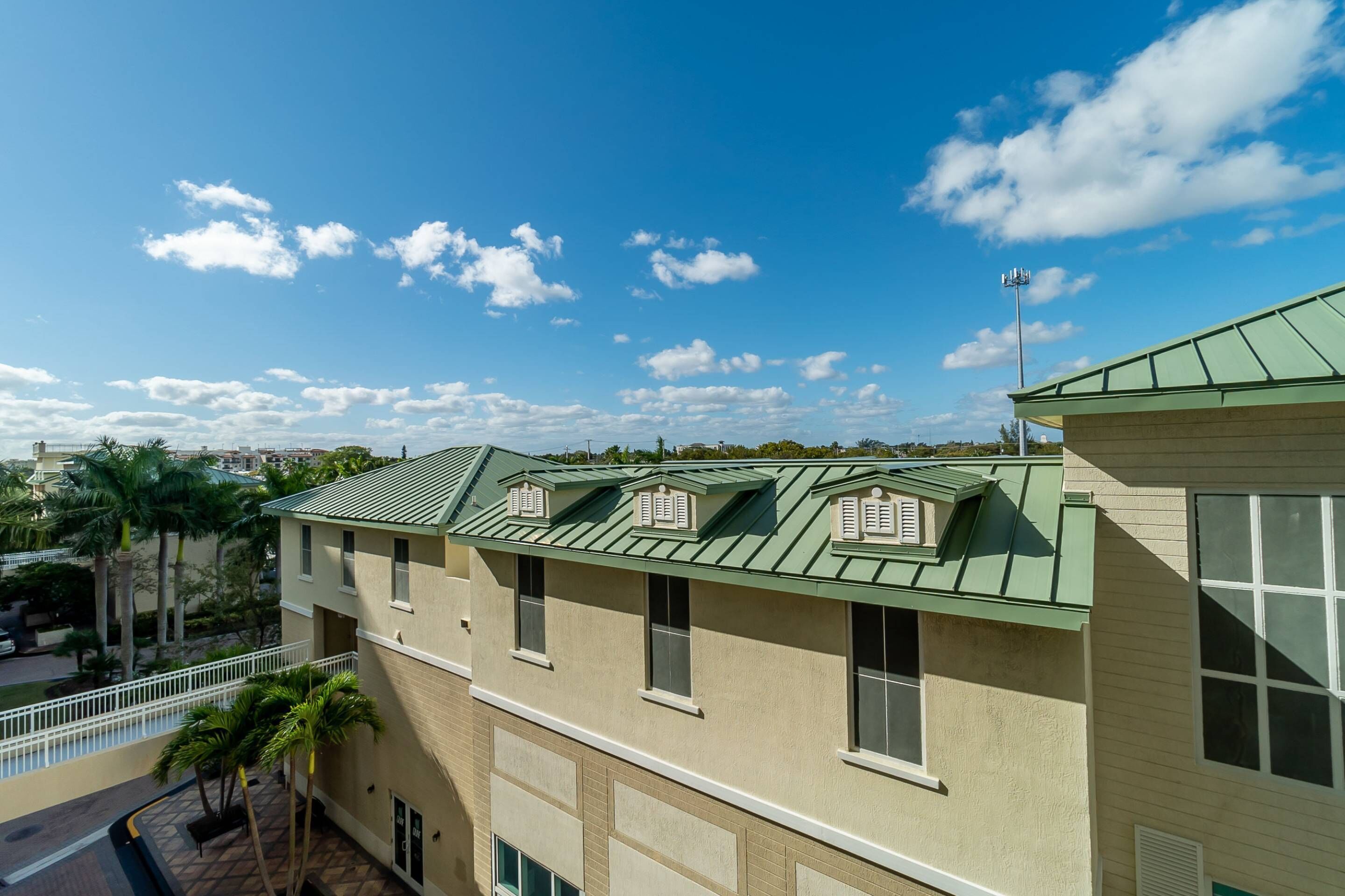 A multi-story building with a green roof and multiple windows.
