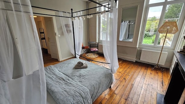 Ein Schlafzimmer mit Himmelbett, einem Fenster mit Aussicht und einer Heizung.