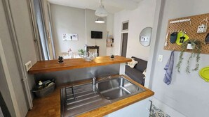 Eine kleine Küche mit Holzarbeitsplatte, Edelstahlspüle und einer Wandtafel mit Küchenutensilien.