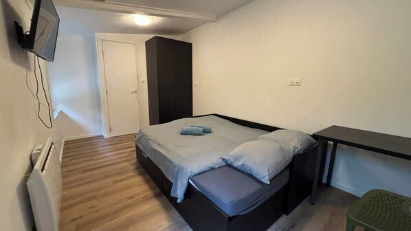A bedroom with a bed, a desk, a chair, a wardrobe, and a TV mounted on the wall. - Grande Maison 14 personnes (Arras)