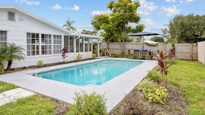 Un jardin avec une piscine, un patio couvert et une clôture en bois.