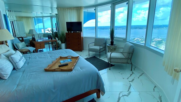 A spacious bedroom with a large bed, a TV, and a view of the sea. -  27th Floor 2BR 2BA incredible views! (Daytona Beach)