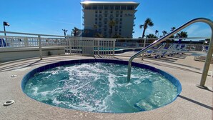 A hot tub area with a pool, a white fence, and a hotel building in the background. -  27th Floor 2BR 2BA incredible views! (Daytona Beach)