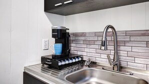 Una cucina moderna con una macchina per il caffè, un lavello e uno schienale.