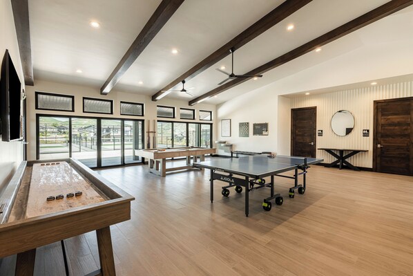 A spacious room with a ping pong table, foosball table, and a billiards table.