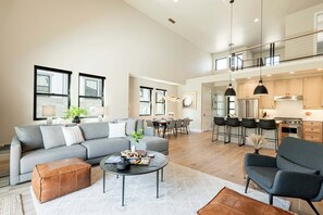 Un vaste espace de vie comprenant un canapé gris, une table basse et un coin repas avec des chaises et une table.