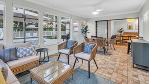 A spacious living area with a sofa, chairs, a coffee table, and a dining table. Large windows provide natural light and views of the outdoors. - Near AMI-Heated Pool-Hot Tub-Game Room-Putting Green-Outdoor Games (Bradenton)
