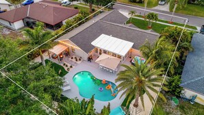An aerial view of a residential property with a swimming pool, patio, and a covered outdoor seating area. - Near AMI-Heated Pool-Hot Tub-Game Room-Putting Green-Outdoor Games (Bradenton)