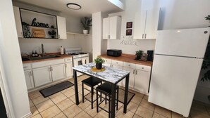A compact kitchen with white cabinets, a marble countertop, a gas stove, a microwave, and a refrigerator. - Timeless Tremont- Enjoy 20% off 5+ nights  (Cleveland)