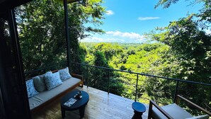 Ein Balkon mit Holzboden, einer Couch mit gemusterten Kissen und einem kleinen Tisch.