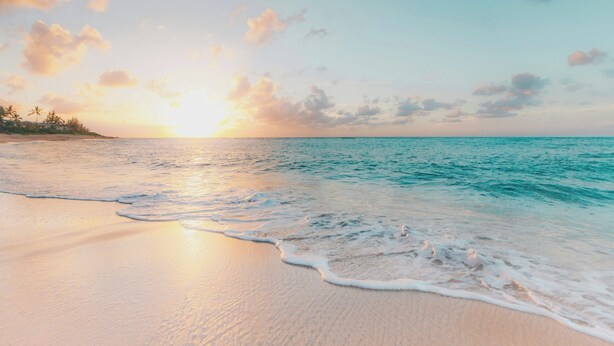 Ein Strand mit sanften Wellen und einem Sonnenuntergang.