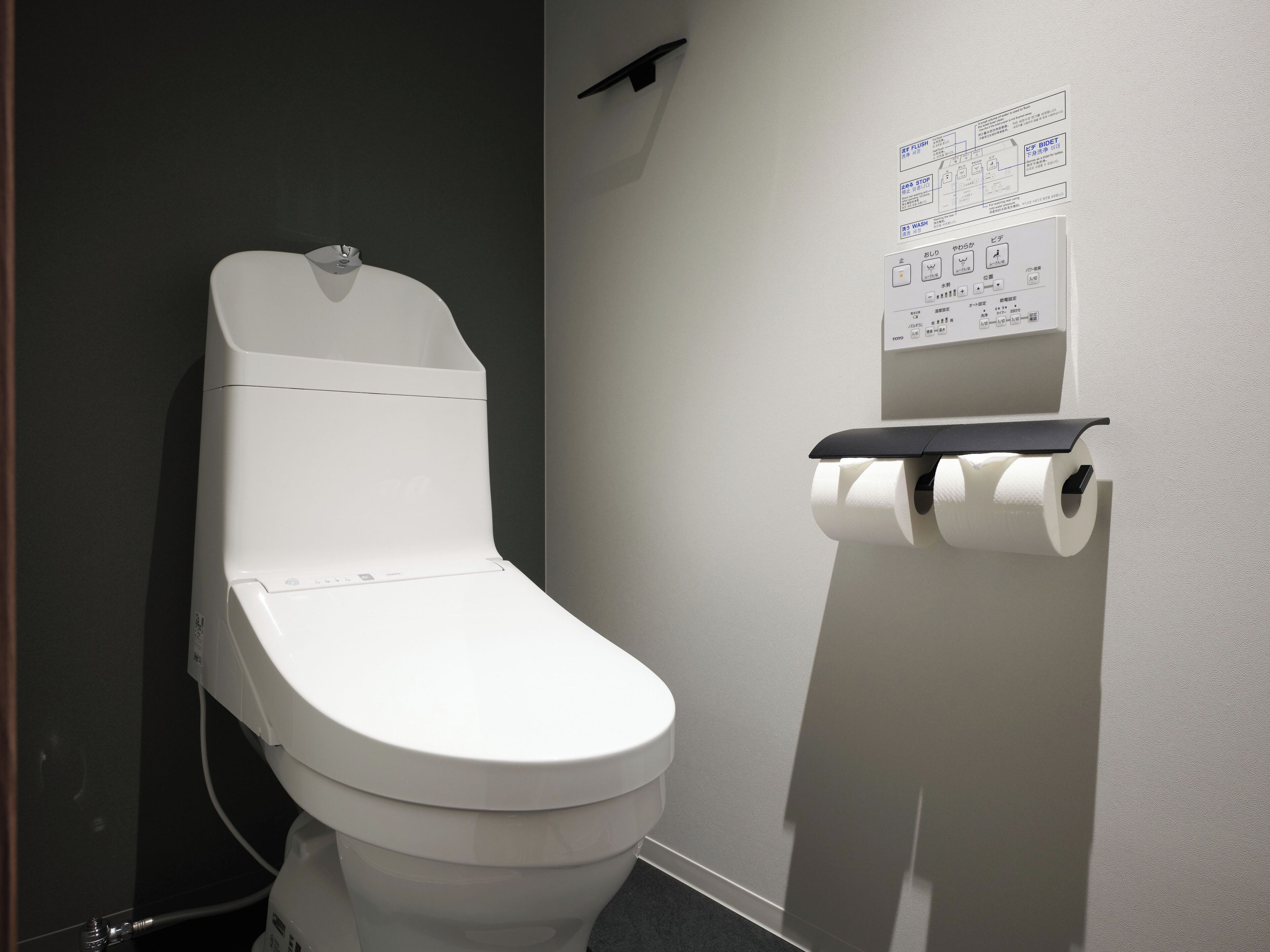 A modern toilet with a flush button and a toilet paper holder.