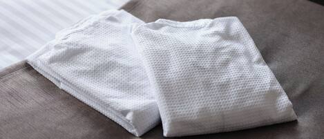 A neatly folded white towel on a gray bed with a striped sheet.