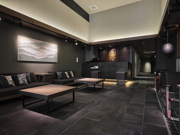 A modern interior with a reception desk, seating area, and a staircase.