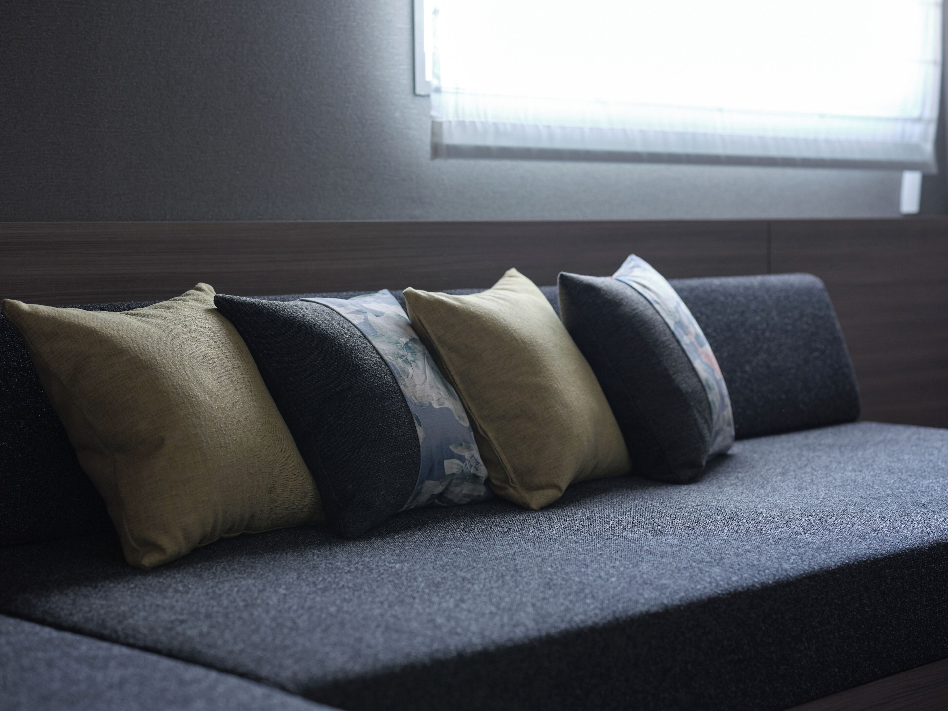 A dark gray sofa with four cushions in various shades and patterns.