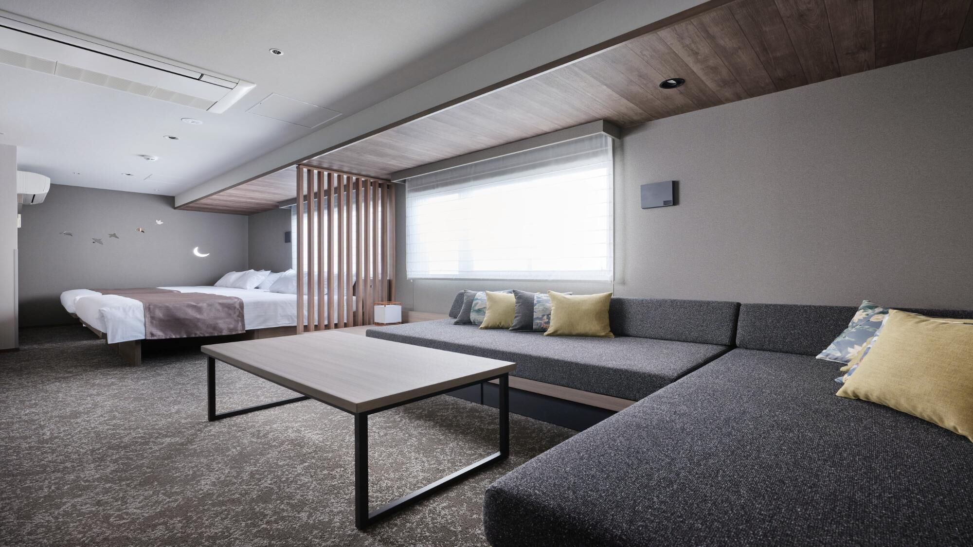 Een moderne hotelkamer met een bed, een bank en een kleine tafel.