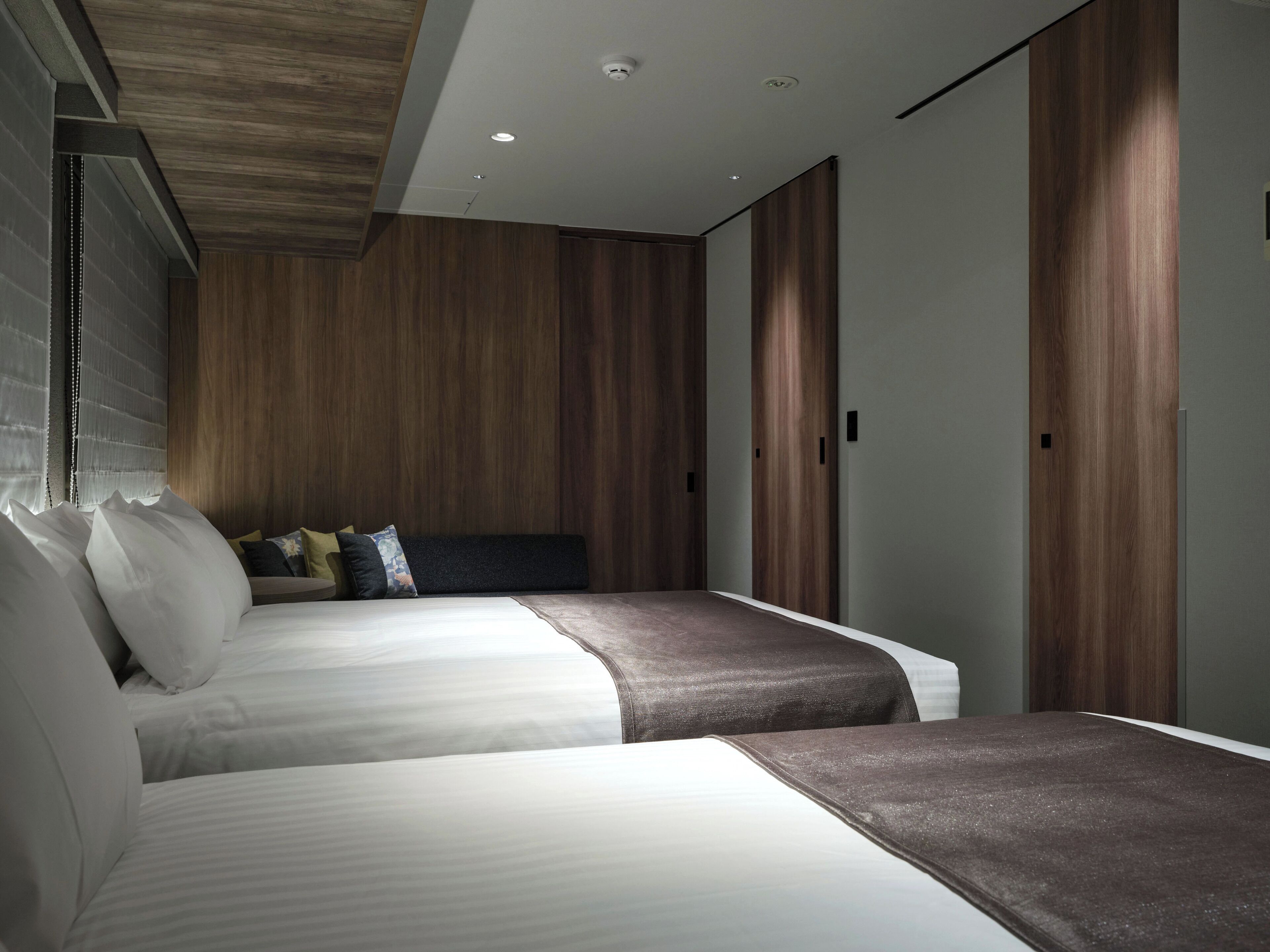 Une chambre moderne avec deux lits, un lambris en bois et une armoire intégrée.