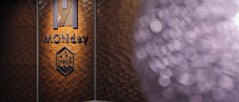 A reception desk with a wooden textured wall and a logo that reads "MONDAY".