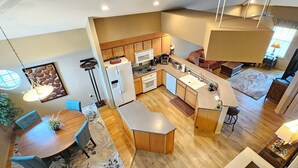 A modern kitchen with wooden cabinets, a central island, and a dining area with a round table and chairs. - 3-Bedroom Condo, Penthouse Suite, Remodeled, Golf Course View, Excellent Rates!! (Branson)