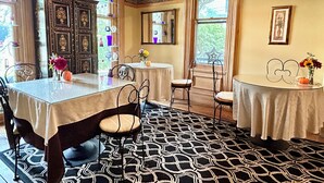 A dining area with a table set for two, a cabinet with decorative items, and patterned flooring. - Jade Room at The Amethyst Inn B&B, jacuzzi, fireplace, antiques and Lancaster   (Adamstown)