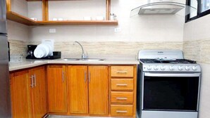 Una cocina con armarios de madera, un lavamanos de acero inoxidable y una estufa.