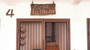 Una doble puerta con un letrero encima, una escalera que da a la entrada, y un acceso empedrado con ladrillos.