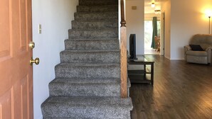 A staircase with a wooden handrail leading to an upper floor. A flat-screen TV is placed on a small table at the bottom of the stairs. - 1,800sf 3 Stories with 8 beds townhome (Casper)