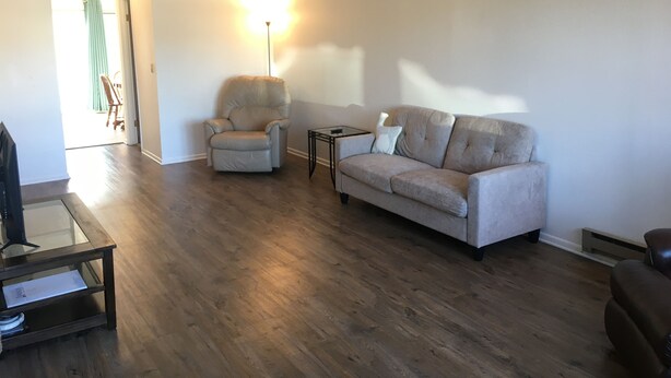 A living room with a sofa, armchair, and glass coffee table. - 1,800sf 3 Stories with 8 beds townhome (Casper)